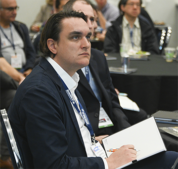 Man in blue suits listening to conference presentation